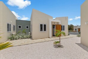 Un edificio moderno con un patio empedrado, una palmera pequeña y una puerta con el número 20.