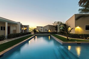 A swimming pool with a clear view of the surrounding buildings and a well-maintained lawn. - 4-person vacation bungalow with shared pool (Willemstad)
