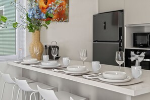 Una cocina moderna con taburetes blancos, una isla central con espacio para comer y un refrigerador grande.