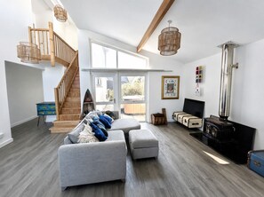 Ein modernes Wohnzimmer mit Treppe, Kamin und großem Fenster.