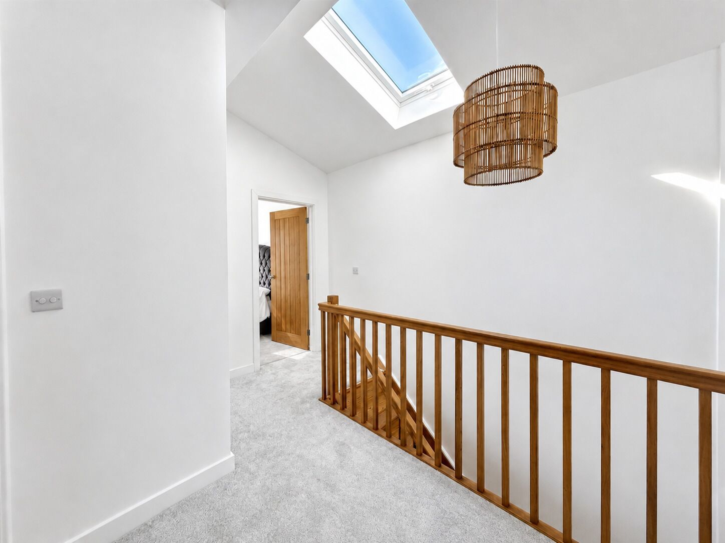 A modern interior with a skylight, a wooden staircase, and a hanging light fixture.