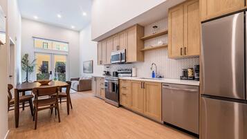 Una cocina moderna con armarios de madera, electrodomésticos de acero inoxidable y un comedor con una mesa redonda y sillas.
