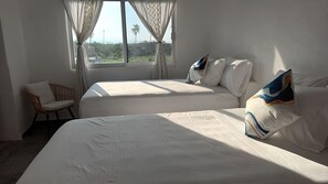 A hotel room with two beds, a chair, and a window with curtains. - BEAUTIFUL PLAYA BLANCA/BARRA DE POTOSI ESCAPE, 2 BEDROOM APT, POOL, SLEEPS 6 (Barra De Potosi)