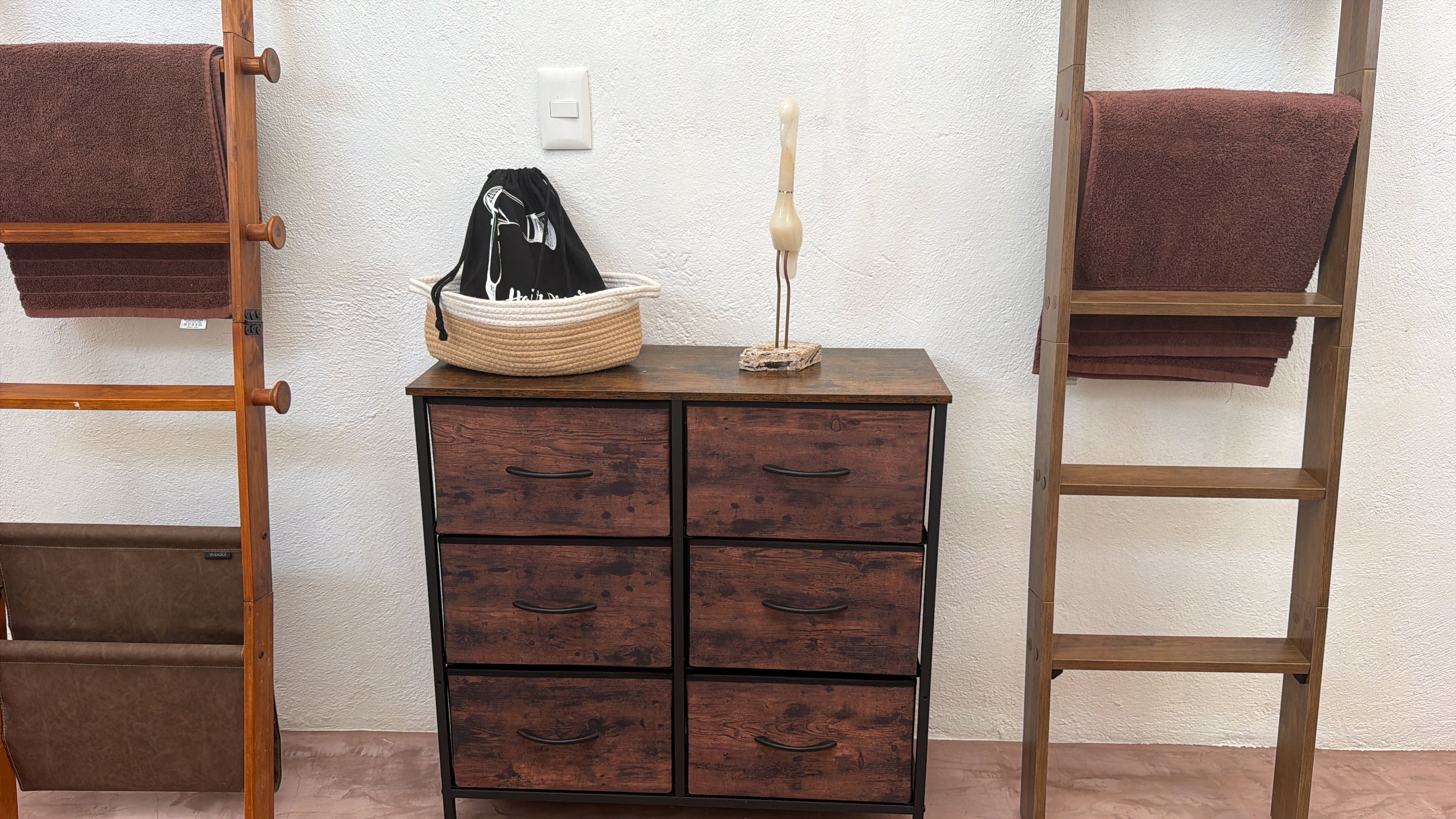 Un comò di legno con sei cassetti, un cesto di vimini e una candela sopra.