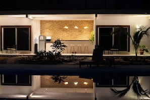 A modern outdoor seating area with a pool, stone wall, and potted plants. - BEAUTIFUL PLAYA BLANCA/BARRA DE POTOSI ESCAPE, 2 BEDROOM APT, POOL, SLEEPS 6 (Barra De Potosi)