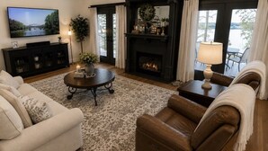 A living room with a fireplace, a television, and a view of a body of water.