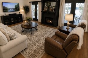 A living room with a fireplace, a television, and a view of a body of water.