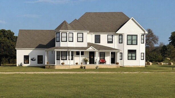 A two-story house with a large front porch, a garage, and a well-maintained lawn.