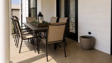 Une terrasse couverte avec une table à manger, des chaises et un ventilateur de plafond.