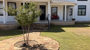 A two-story house with a covered porch and a small tree in the front yard.