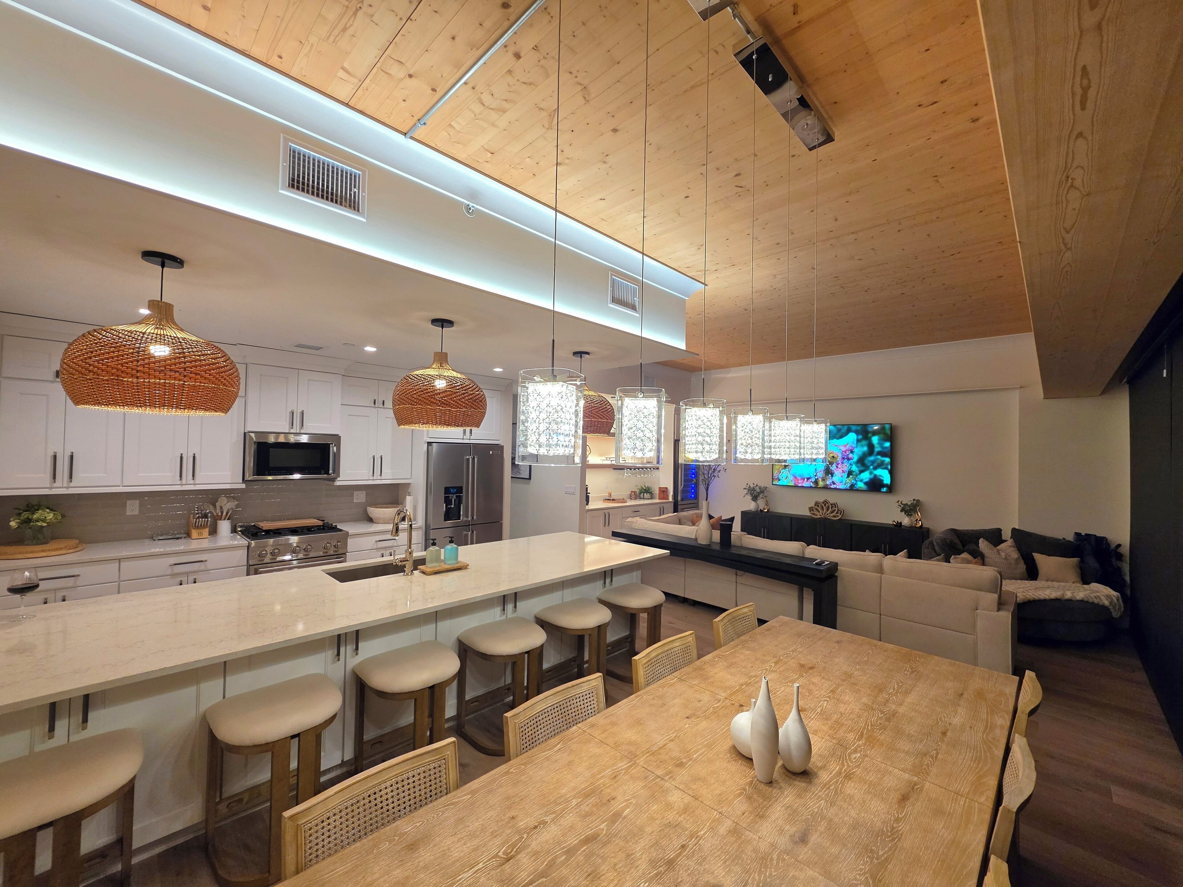 Una cocina moderna con armarios blancos, electrodomésticos de acero inoxidable y una isla grande con taburetes de bar.