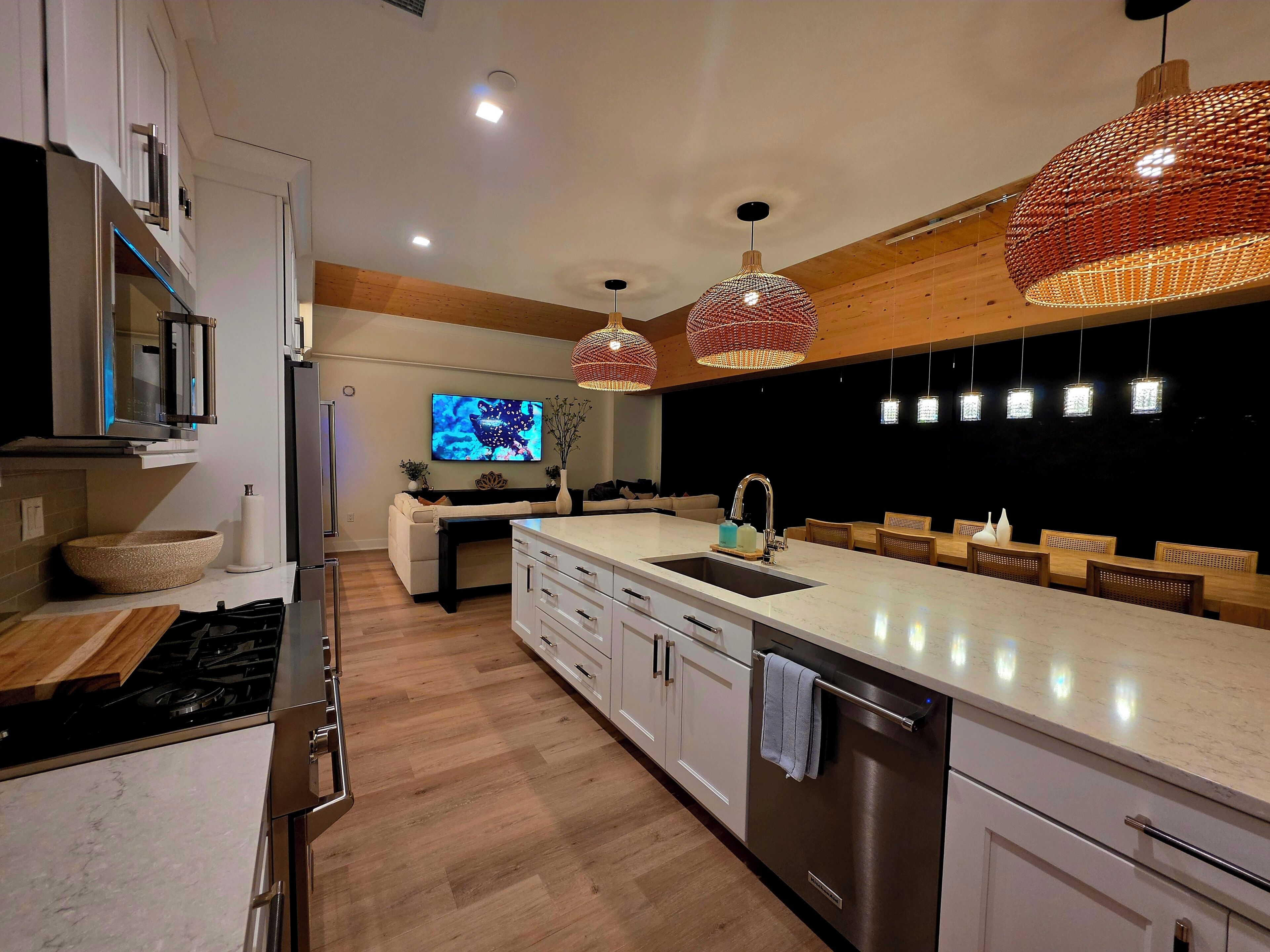 Una cocina moderna con una isla grande, electrodomésticos de acero inoxidable e iluminación colgante.