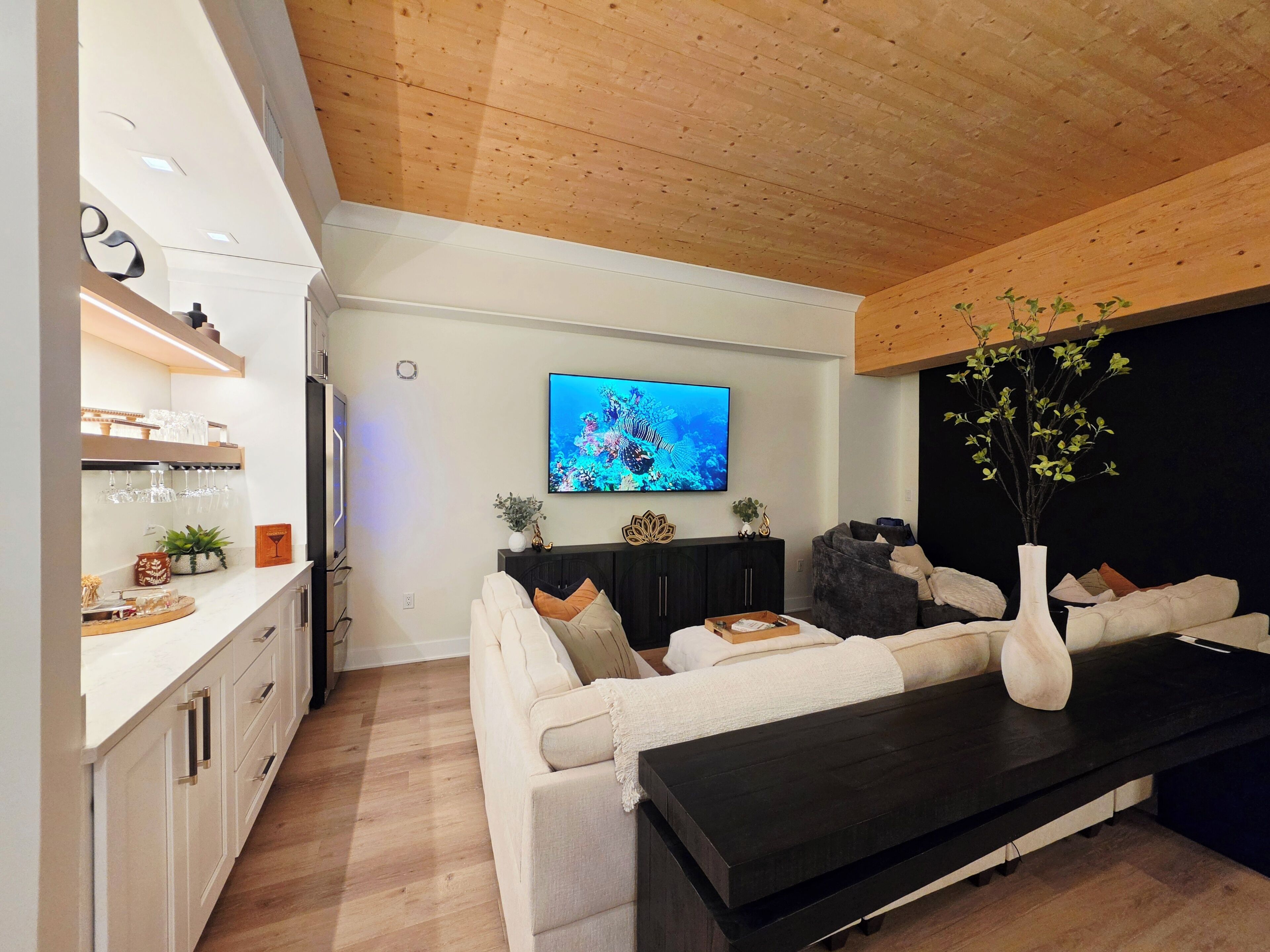 Una sala moderna con un sofá, una mesa de centro y un televisor montado en la pared.