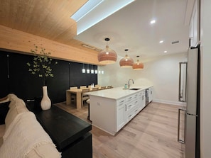 A modern kitchen with a central island, wooden flooring, and pendant lighting.