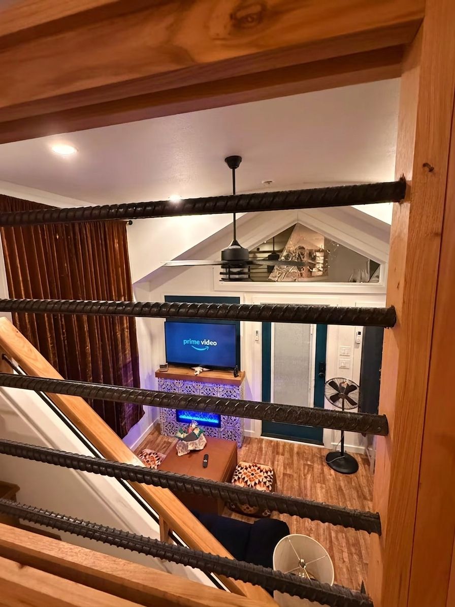 A staircase with a wooden railing leading to a living area with a television displaying 'prime video'.