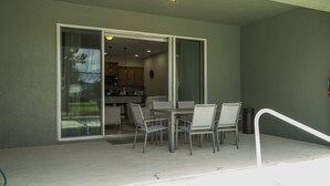Ein Balkon mit Tisch und Stühlen, eine Schiebetür zu einer Küche und ein Feuerlöscher an der Wand.