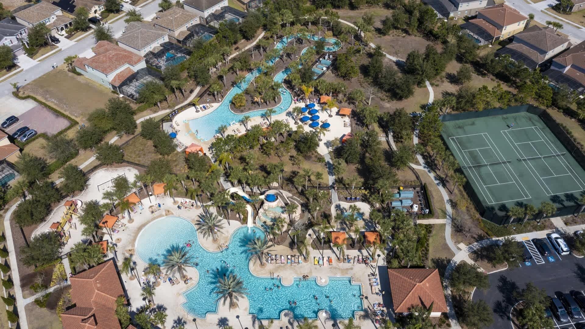 Vista aérea de un resort con varias piscinas, una cancha de tenis y diversas comodidades.