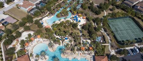 An aerial view of a resort with multiple swimming pools, a tennis court, and a variety of amenities.