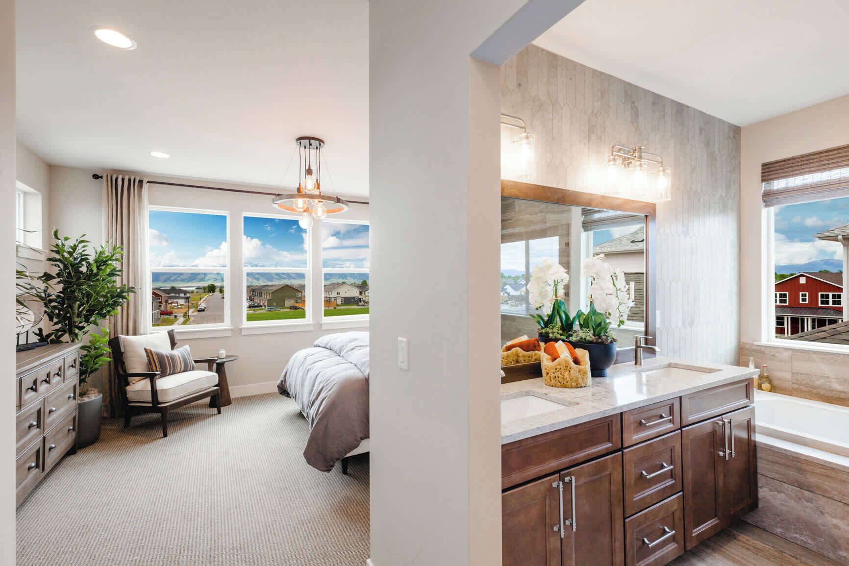 A bedroom with a bed, a chair, a dresser, and a window with a view of houses.