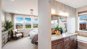 A bedroom with a bed, a chair, a dresser, and a window with a view of houses.