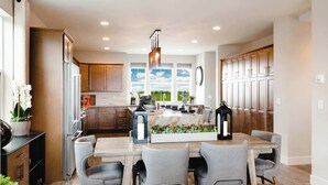 A modern kitchen with a central island, wooden cabinets, and a view of the outdoors. - Iconic Big Sky Getaway | Epic Yellowstone Retreat! (Belgrade)
