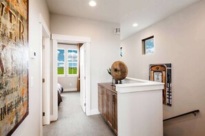 Un couloir comprenant un lit, une armoire en bois, un téléphone fixé au mur et une porte donnant sur une pièce avec vue sur l’extérieur.