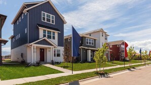 Un quartier résidentiel avec des maisons modernes à deux étages, un ciel dégagé et une pelouse bien entretenue.