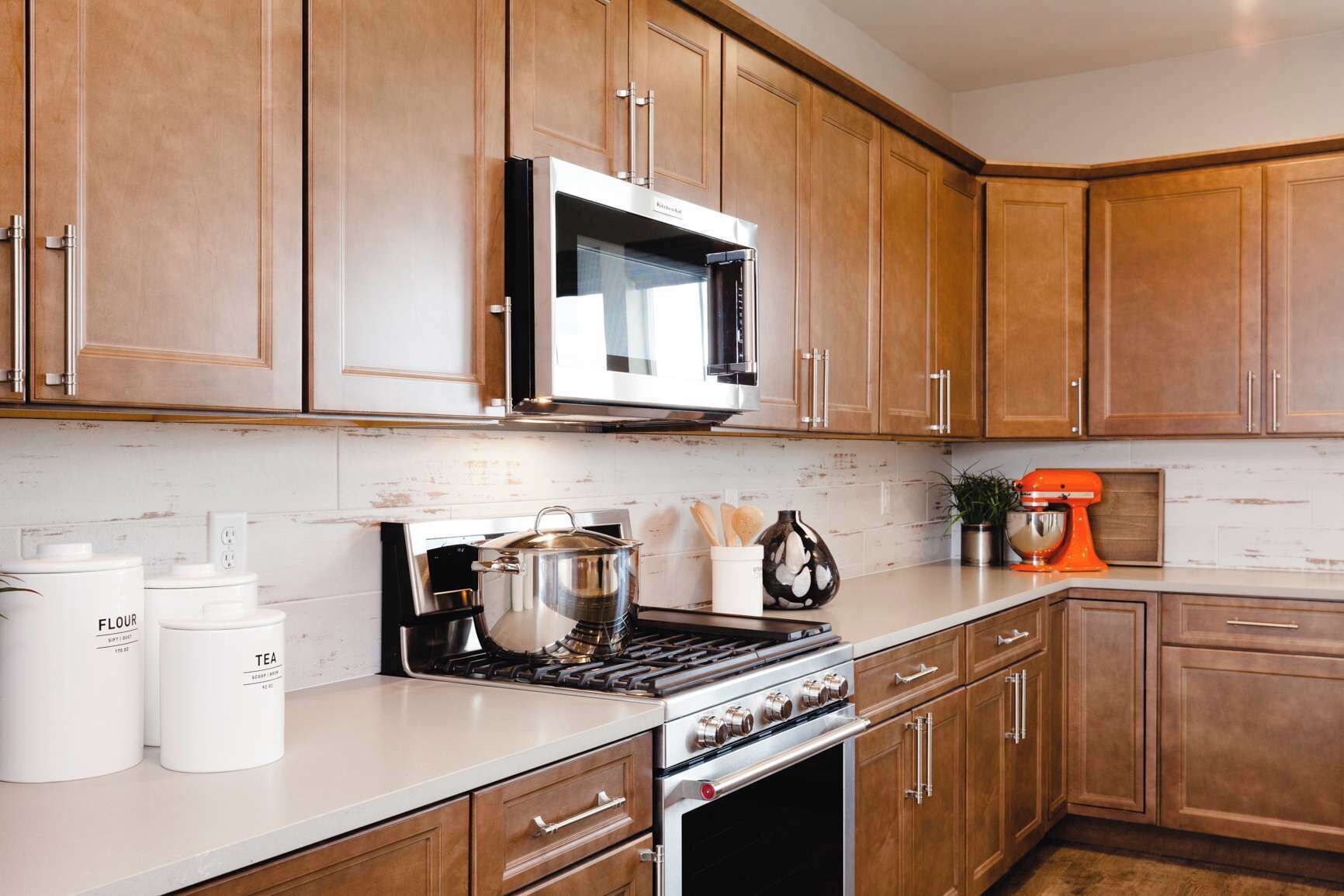 A kitchen with wooden cabinets, a stainless steel range, a microwave, and a stand mixer.