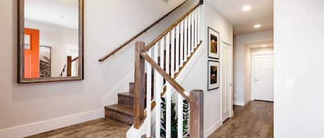 A staircase with wooden steps and white railings, leading to a door.