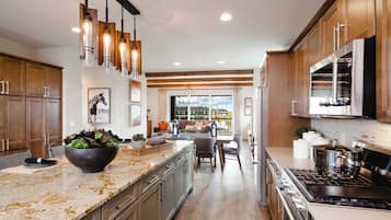 Una cocina moderna con encimeras de granito, electrodomésticos de acero inoxidable y armarios de madera.