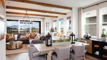 Una sala de estar moderna con una mesa de comedor de madera, sillas tapizadas en gris y un sofá con cojines coloridos.