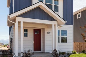 A two-story residential building with a red door, a small porch, and a mailbox. - Iconic Big Sky Getaway | Epic Yellowstone Retreat! (Belgrade)