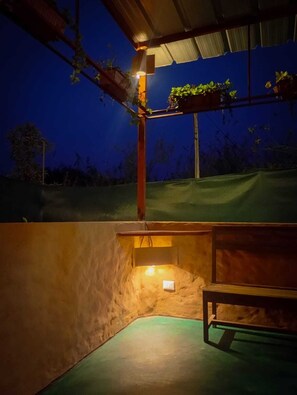 A covered outdoor area with a bench, a small table, and a light fixture.