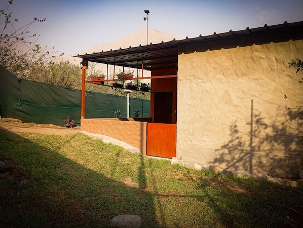 A small building with a covered porch, a door, and a solar panel on the roof.