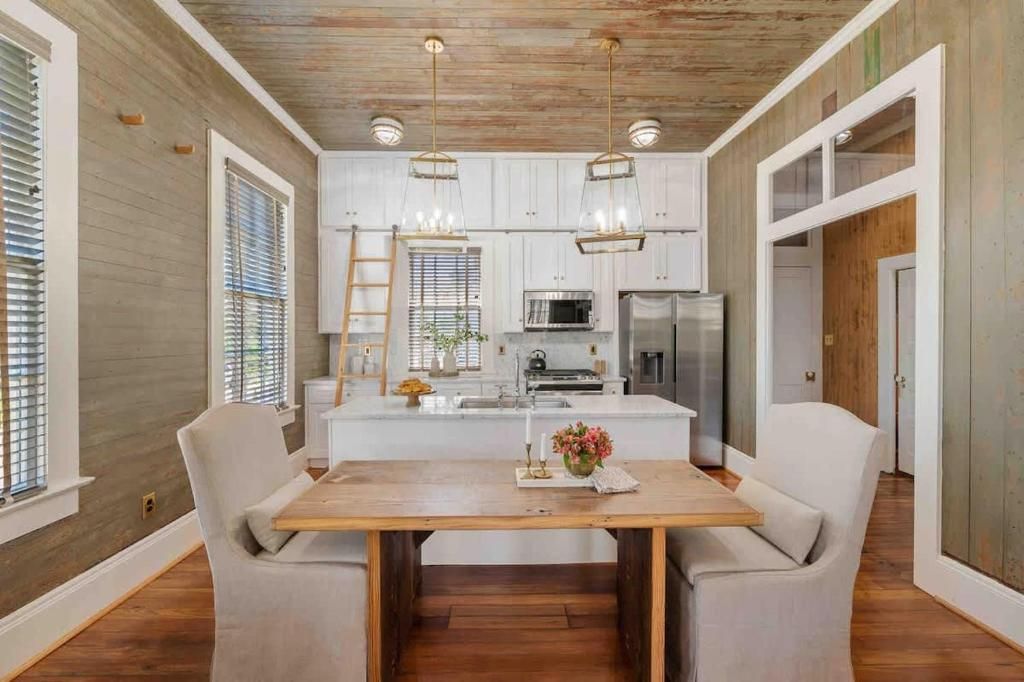 Una cocina moderna con gabinetes blancos, una isla central e iluminación colgante.
