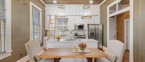 Una cocina moderna con gabinetes blancos, una isla central e iluminación colgante.