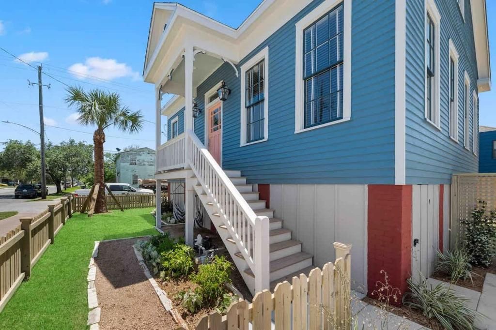 Une maison à deux étages avec un porche à l’avant, un escalier et un petit jardin.