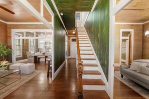 A spacious interior with a wooden staircase, a dining area, and a living room. - Rustic Luxury from Restoring Galveston (Galveston)