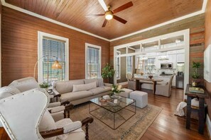 A spacious living area with a sofa, chairs, a coffee table, and a kitchen in the background. - Rustic Luxury from Restoring Galveston (Galveston)