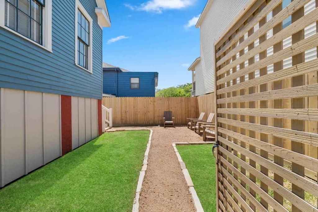 A backyard with artificial grass, a wooden fence, and a garage door.