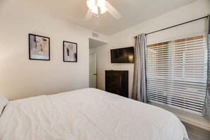 A bedroom with a bed, a ceiling fan, a TV mounted on the wall, and a window with blinds. - I114 – Private King Retreat | DFW 10 Min | Yard+W/D (Irving)