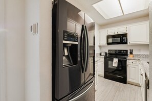Een moderne keuken met een zwarte koelkast, magnetron, oven en een inbouwoven.