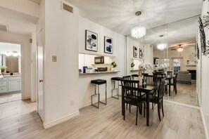 A modern kitchen with a dining area, white walls, and a chandelier. - I114 – Private King Retreat | DFW 10 Min | Yard+W/D (Irving)