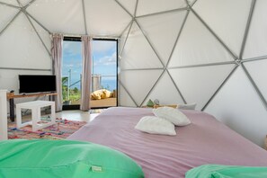 A tent-style room with a bed, a television, and a view of the outdoors.