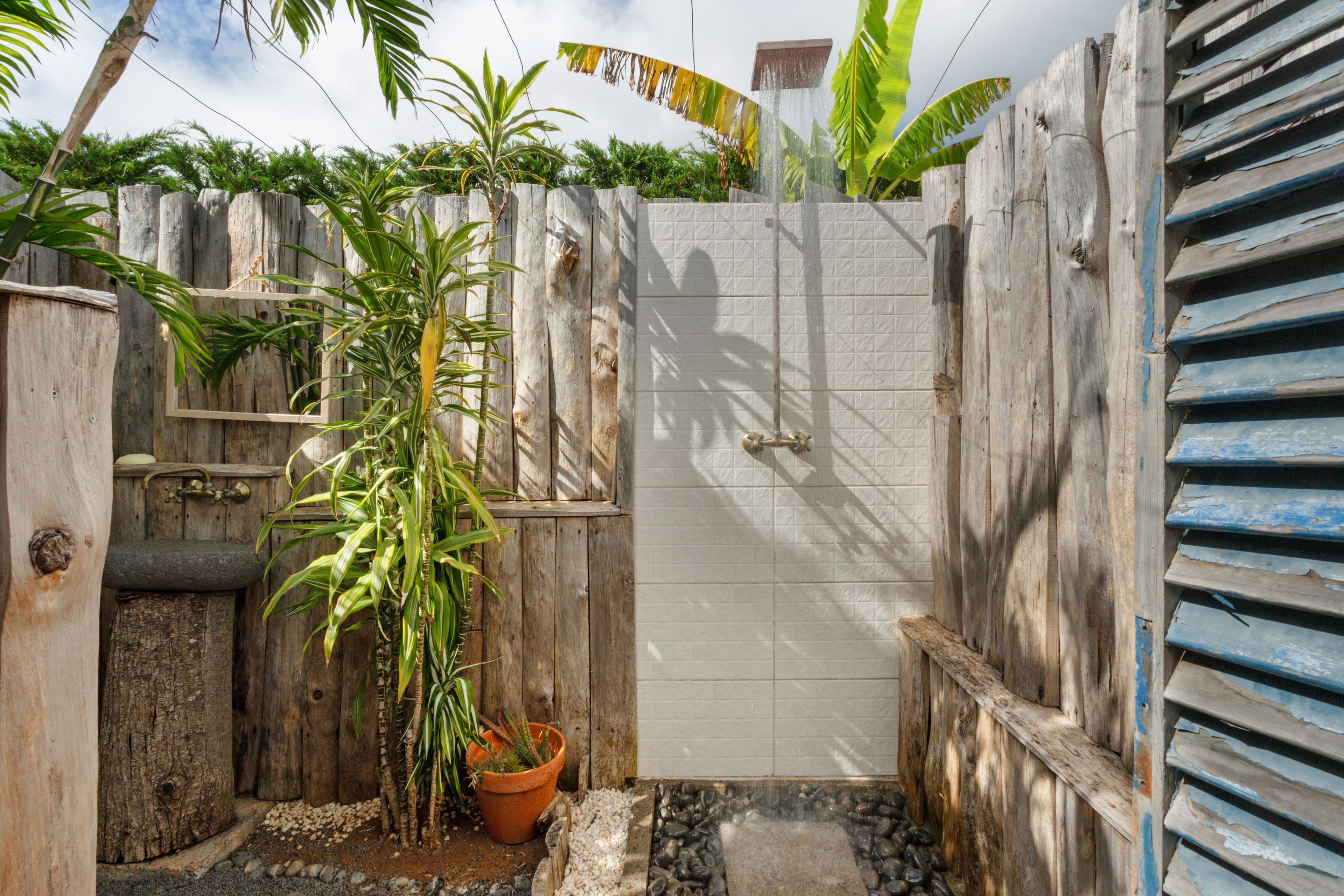 Una puerta de madera con un portón de metal, rodeada de plantas y una pequeña fuente.
