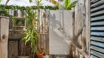 Una puerta de madera con un portón de metal, rodeada de plantas y una pequeña fuente.