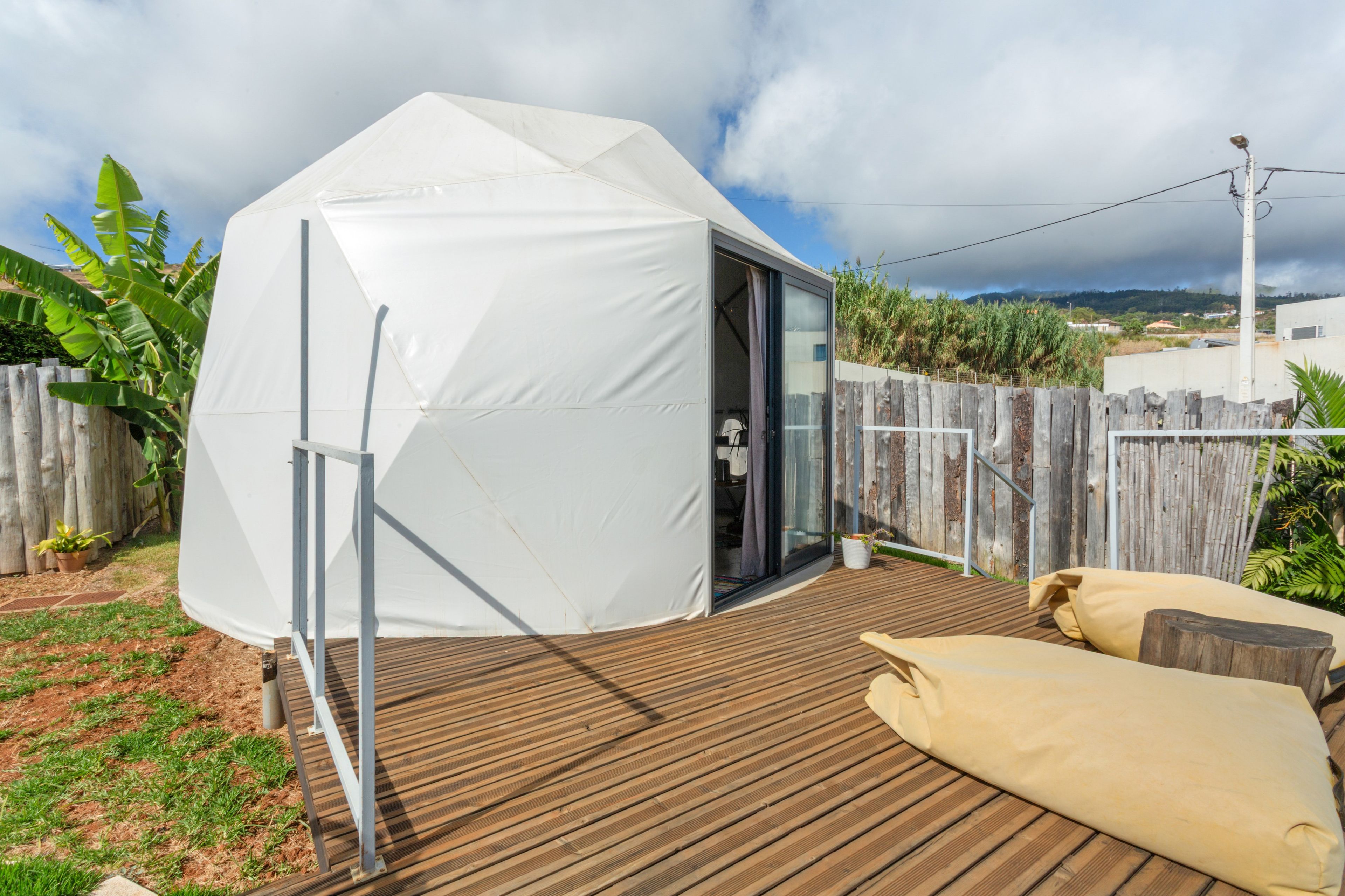A tent-like structure with a door, a wooden deck, and a fence in a backyard setting.