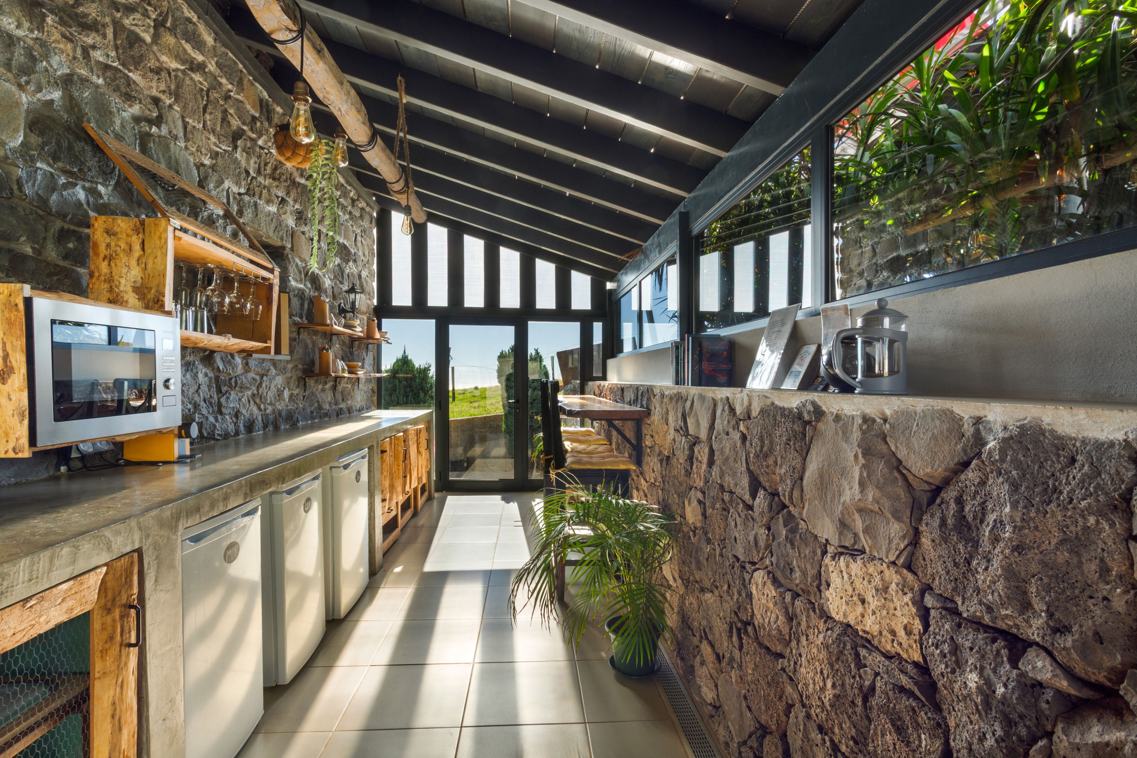 Una cocina moderna con paredes de piedra, armarios de madera y un amplio ventanal.
