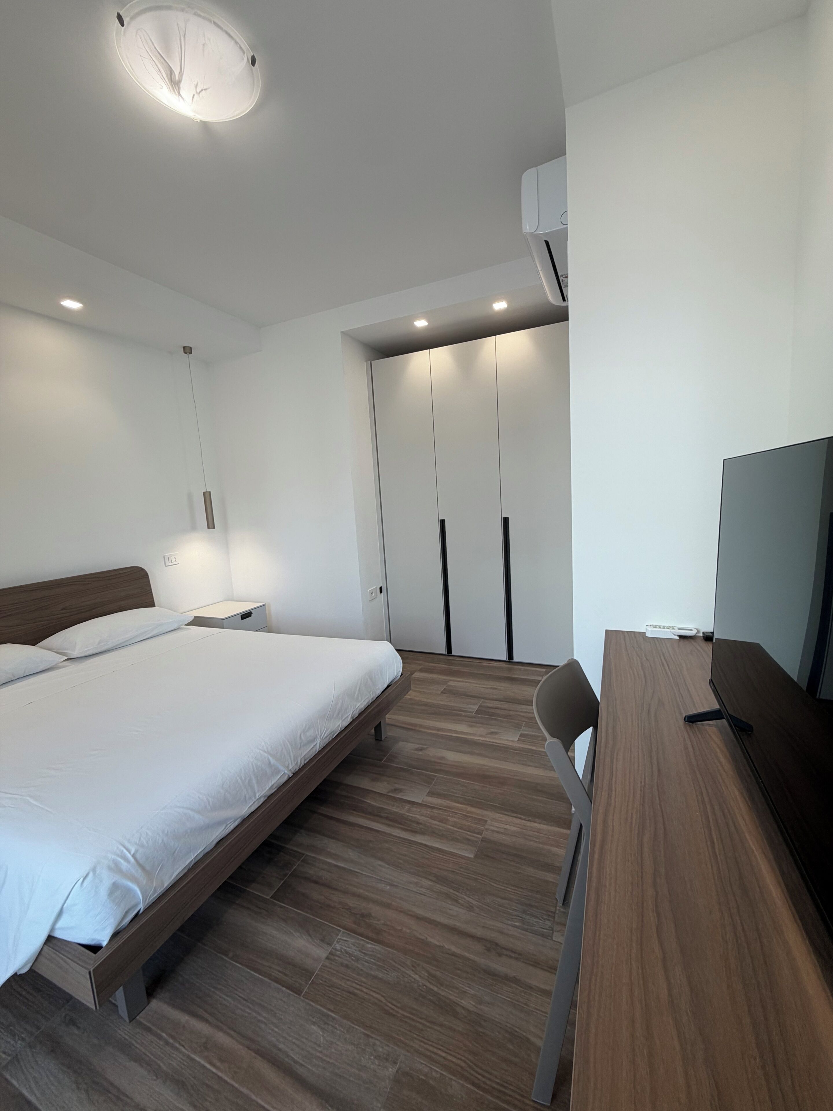 A modern bedroom with a bed, bedside table, and a TV.