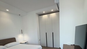 A modern bedroom with a bed, bedside table, and a TV. - Le Calendule Luxury Apartment (Olbia)